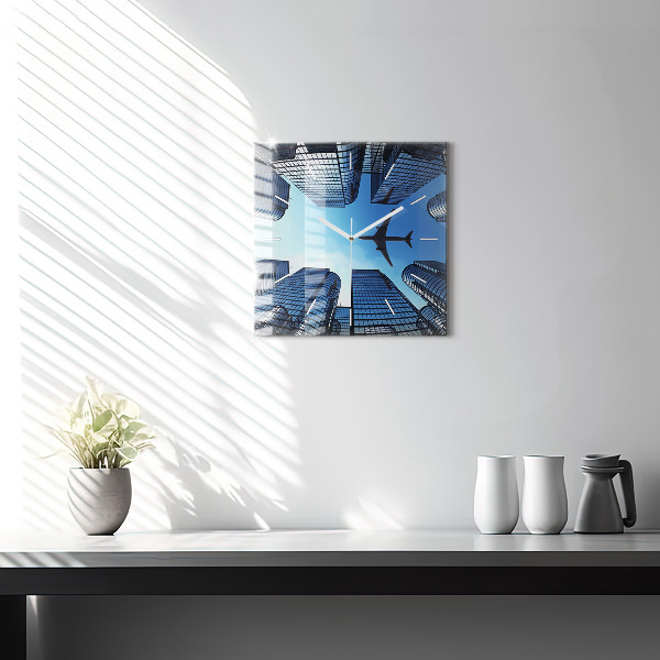 Horloge carrée en verre Avion au-dessus des bâtiments